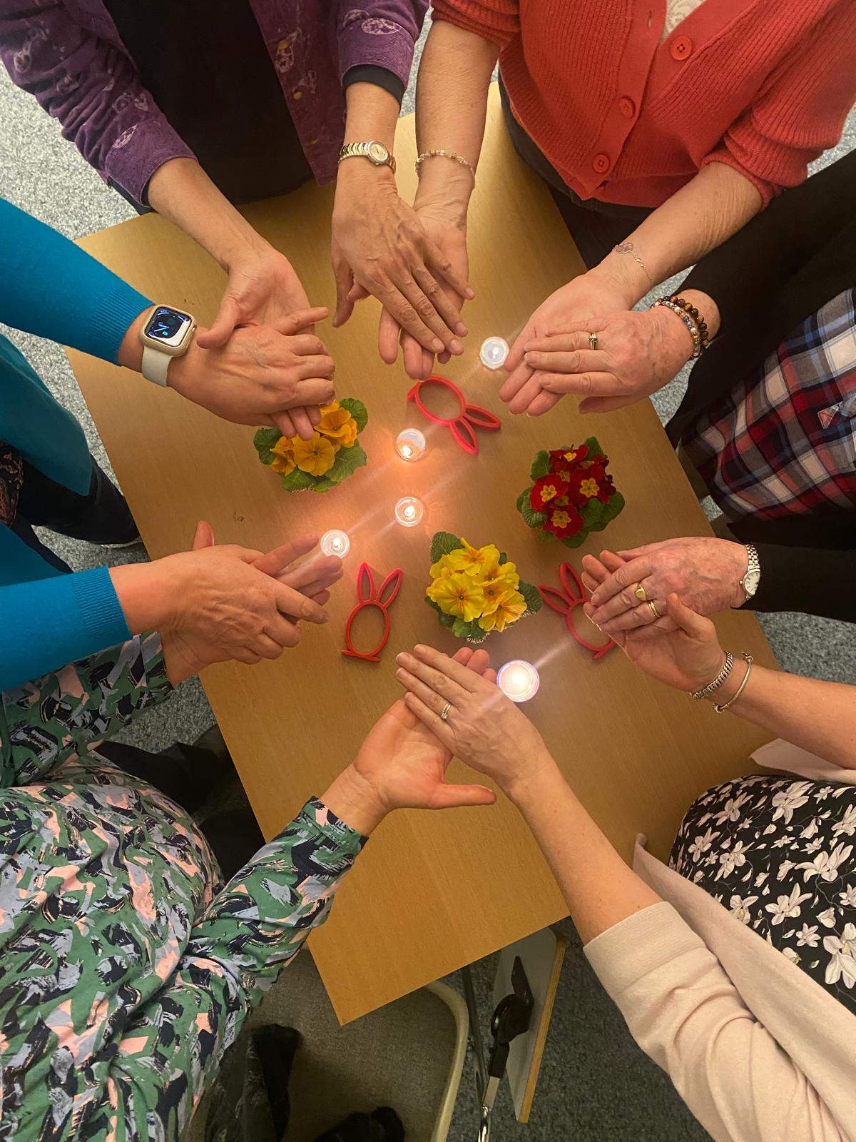 Les mains des participantes réunies autour des bougies lors d'une rencontre du Café-deuil